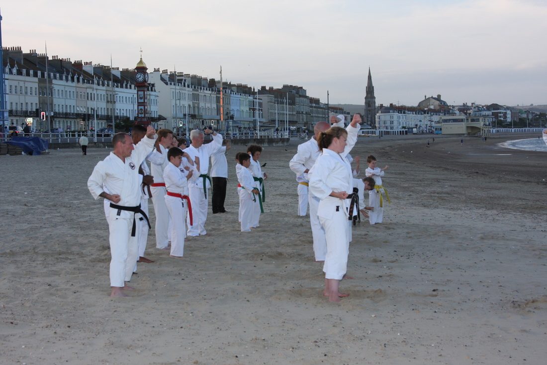 Students and instructors training in gis on a sandy beach with the seafront behind them