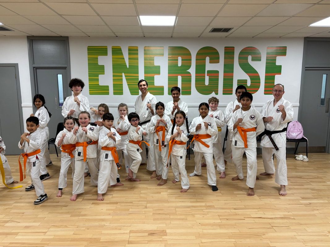 Children wearing their new belts alongside instructors after the regional grading, March 2025