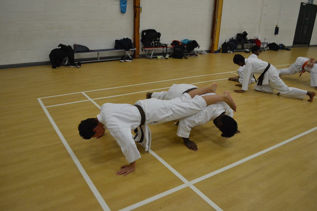 Students doing press ups on their knuckles on the hall floor