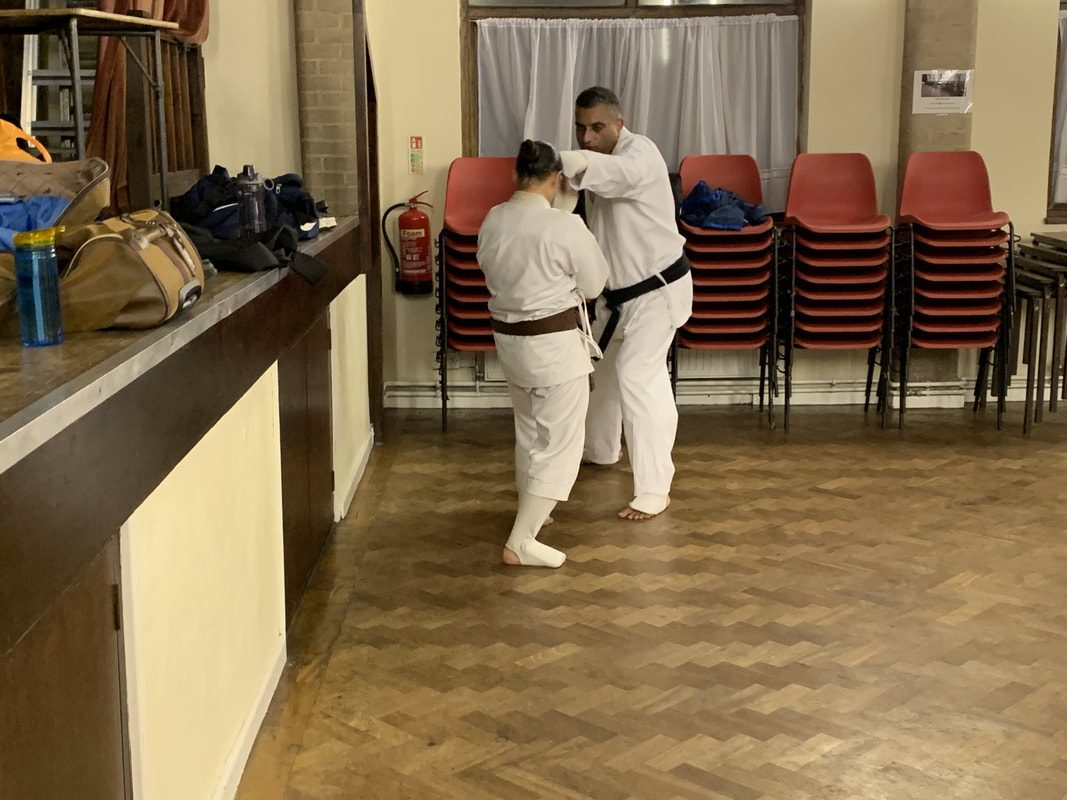An instructor demonstrating a self defence hold on a partner in a community hall